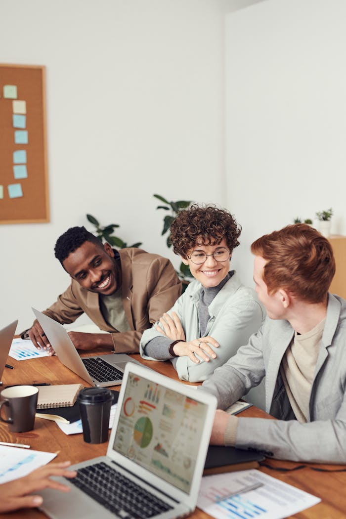 Diverse team engaged in a brainstorming session in a modern office space with laptops and documents.
